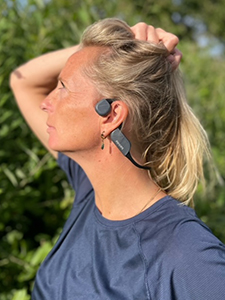Žena nosi bluetooth slu&scaron;alice tvrtke Philips koje zvuk prenose preko kostiju